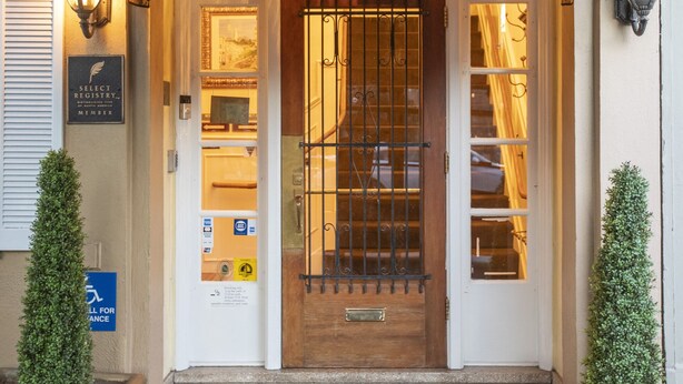 Een hotel ingang met het nummer '1660' boven de deur, een deurbel en een bord dat Select Registry-lidmaatschap aangeeft.