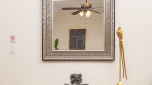 Een houten dressoir met drie lades, een lijst met spiegel erboven en een gouden lamp ernaast.