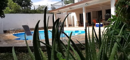 Una piscina al aire libre, sombrillas, sillones reclinables de piscina