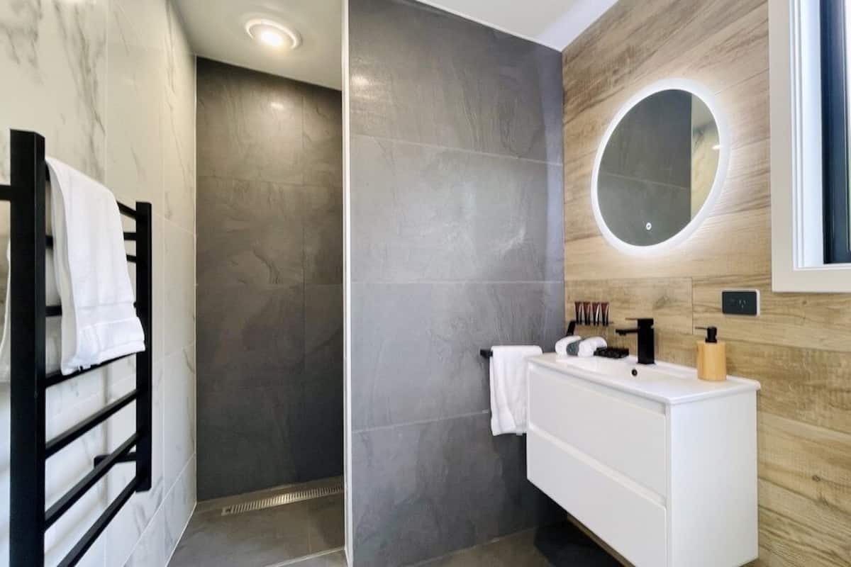 Un baño moderno con cabina de ducha, tocador con espejo y inodoro.