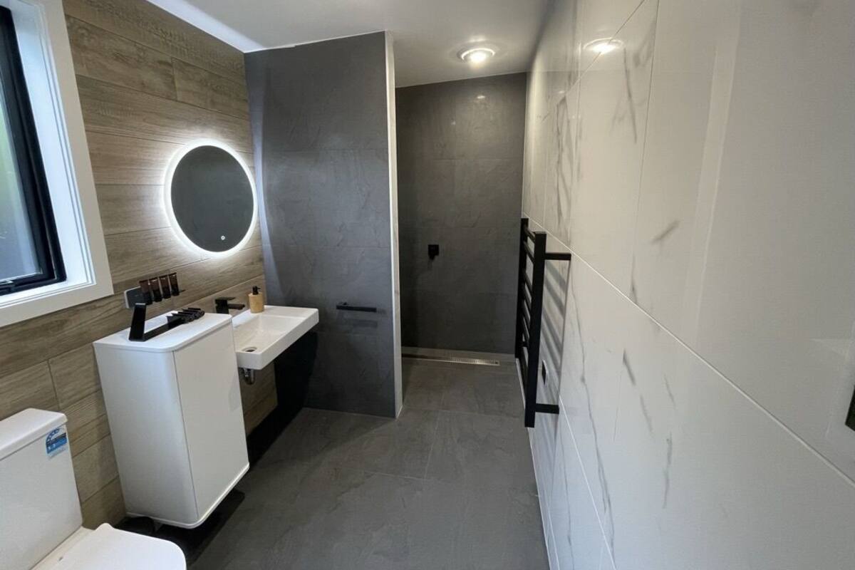 Un baño moderno con inodoro, lavabo y zona de ducha.