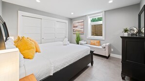 A bedroom with a large bed, a built-in wardrobe, a window with a view, and a bedside table with a lamp. - BOOK 7 NITES AND GET A DISCOUNT 2 BEDROOM PRIVATE UNIT (Portland)