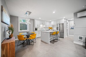 A modern kitchen with white cabinets, a central island, and yellow chairs. - BOOK 7 NITES AND GET A DISCOUNT 2 BEDROOM PRIVATE UNIT (Portland)
