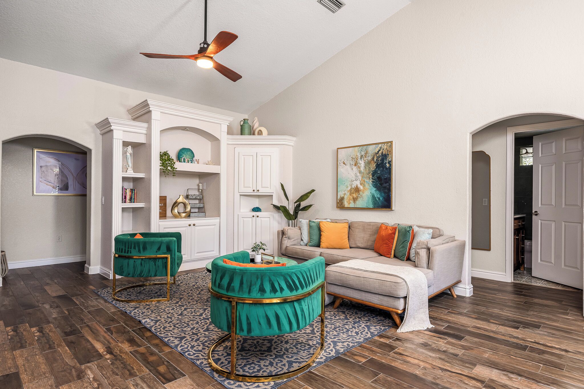 A living room with a white fireplace, a beige sofa, and two green armchairs.