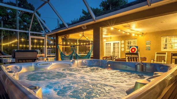 A hot tub with a hammock, string lights, and a patio area with chairs and tables. - Near Downtown &Beach! Games! Private Pool! Hot Tub (Bradenton)