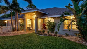A two-story house with a covered porch, a well-maintained lawn, and tropical plants. - Near Downtown &Beach! Games! Private Pool! Hot Tub (Bradenton)