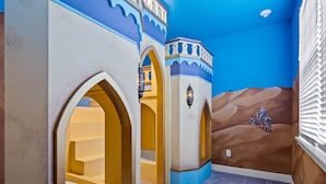 A room with a desert-themed mural, arched doorways, and a carpeted floor. - Arcades, Pool Table, Craps Table, Huge Galactic Bedroom: Magic Moments (Kissimmee)