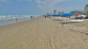 A sandy beach with umbrellas and beach chairs. - Heated Pool & Hot Tub!  Fall and Winter SPECIAL! (South Padre Island)