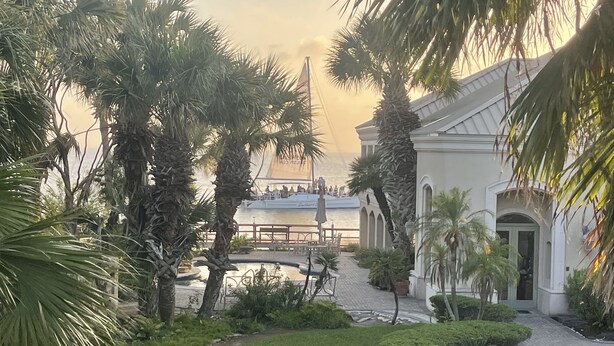 A courtyard with palm trees, a pathway, and a building with a white facade. - Heated Pool & Hot Tub!  Fall and Winter SPECIAL! (South Padre Island)