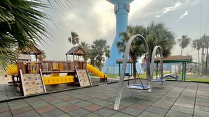 A playground with a climbing wall, a slide, and swings. - Heated Pool & Hot Tub!  Fall and Winter SPECIAL! (South Padre Island)
