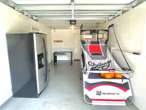Eine Garage mit einem Kicker, einem Kühlschrank und einem Sportwagen.