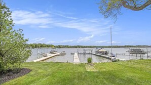A marina with docks and boats, surrounded by a grassy area and trees.
