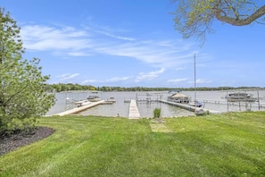 A marina with docks and boats, surrounded by a grassy area and trees. - Lumos House on Magician Lake (Dowagiac)