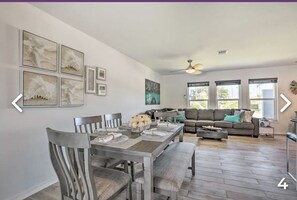 Uma sala de estar espaçosa com área de jantar, janelas amplas e ventilador de teto.