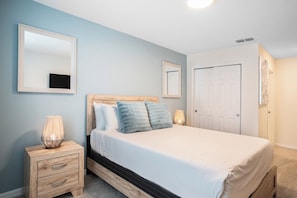 A bedroom with a bed, bedside tables, a mirror, and a door. - Pool Oasis: 5BR Townhome w Game Room Fun (Kissimmee)