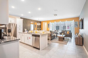 A modern kitchen with a central island, built-in appliances, and a dining area with a sofa and coffee table.