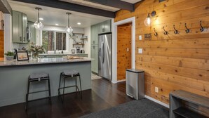 Une cuisine moderne dotée d’un îlot central, d’appareils électroménagers en acier inoxydable et d’éléments décoratifs en bois.