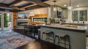 Une cuisine moderne dotée d’un grand îlot central, de tabourets de bar et offrant une vue sur l’extérieur.