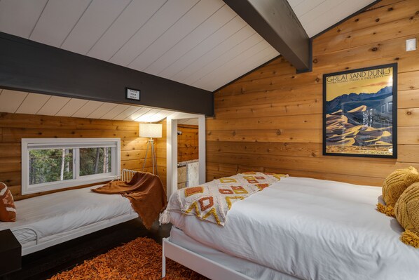 Une cabine équipée de deux lits, d’une fenêtre, d’une lampe et d’une affiche accrochée au mur.