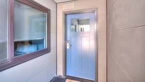 A door with a number plate, a window with a view, and a door mat. - Suite 218 - 1BR Apartment, King Bed, Kitchen, 2nd (Rapid City)