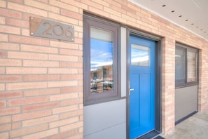 Un bâtiment avec une porte bleue, une fenêtre et un mur en briques.