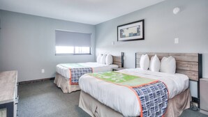 A hotel room with two beds, a window, a framed picture, and a ceiling light.