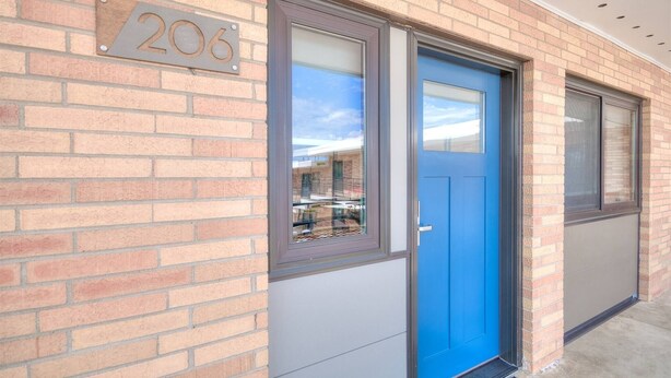 A brick building with a blue door, a window, and a number sign.