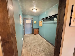 A hallway with a blue door, a bulletin board, and a coat rack.
