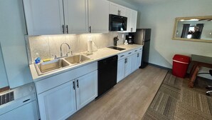 A modern kitchen with white cabinets, a black microwave, and a dishwasher.