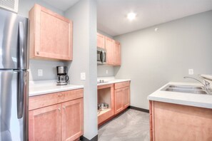 A kitchen with stainless steel appliances, wooden cabinets, a microwave, and a sink.