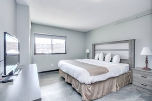 Une chambre d’hôtel moderne dotée d’un grand lit, d’une télévision à écran plat, d’un bureau et d’une fenêtre donnant sur la ville.