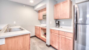 A kitchen with wooden cabinets, a stainless steel refrigerator, and a built-in microwave.
