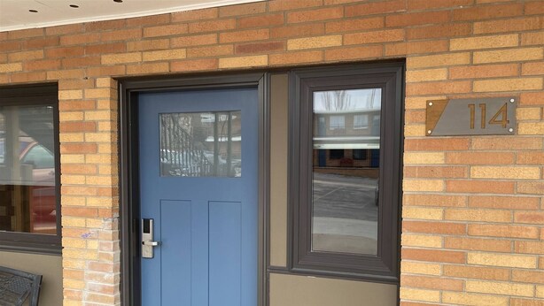 A blue door with a window, a number plaque, and a brick wall. - 1BR with 2 beds and a kitchen on the main floor (Rapid City)