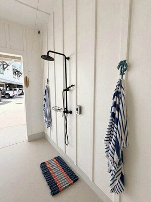 A hallway with a shower, a towel rack, and a rug.