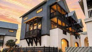 Une maison moderne à deux étages, dotée d’un balcon, d’un mur en pierre et d’une pelouse bien entretenue.