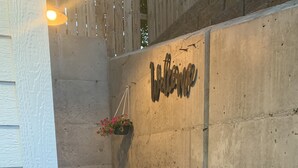 A concrete wall with a 'Welcome' sign, a hanging flower pot, and a small potted plant. - Wine Country Guest House (Kennewick)