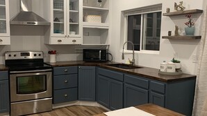 A modern kitchen with white cabinets, a stainless steel oven, a microwave, and a wooden dining table. - Wine Country Guest House (Kennewick)