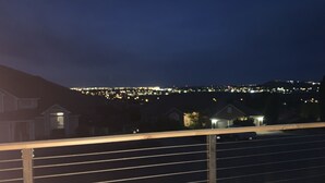 A nighttime view from a balcony with a railing, overlooking a cityscape with illuminated buildings. - Wine Country Guest House (Kennewick)