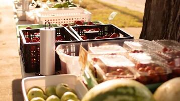 A table with various fruits and vegetables, including apples, watermelons, and tomatoes, arranged outdoors.