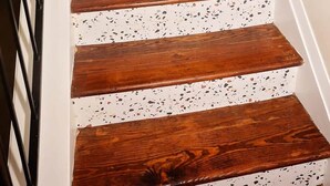 Un escalier avec des marches en bois et des murs blancs ornés de motifs pointillés.