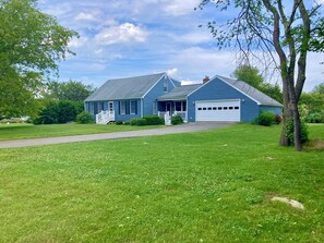 A two-story blue house with a front porch, a garage, and a well-maintained lawn.