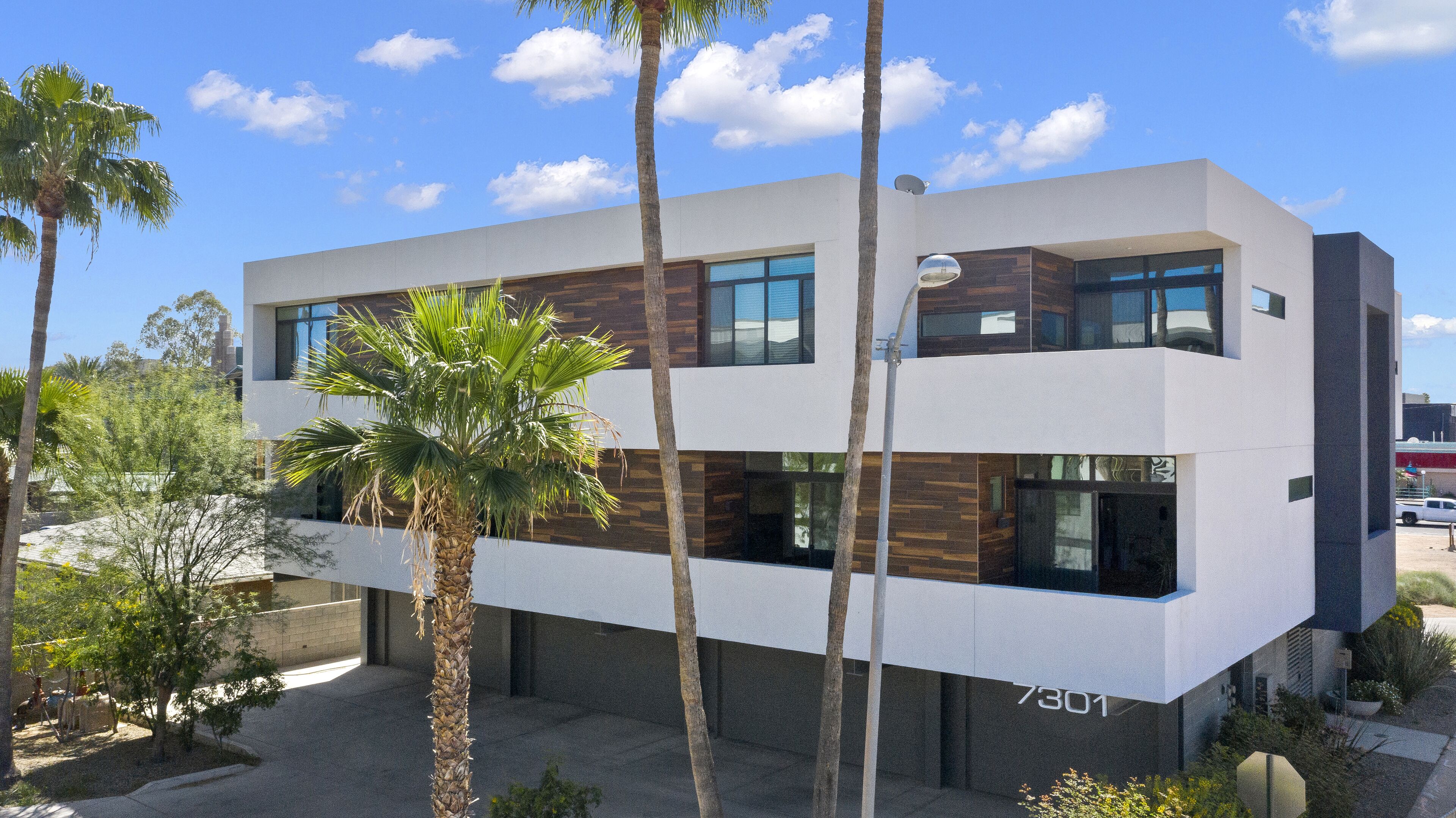 Un edificio moderno de dos pisos con techo plano, ventanas grandes y un número de dirección visible.