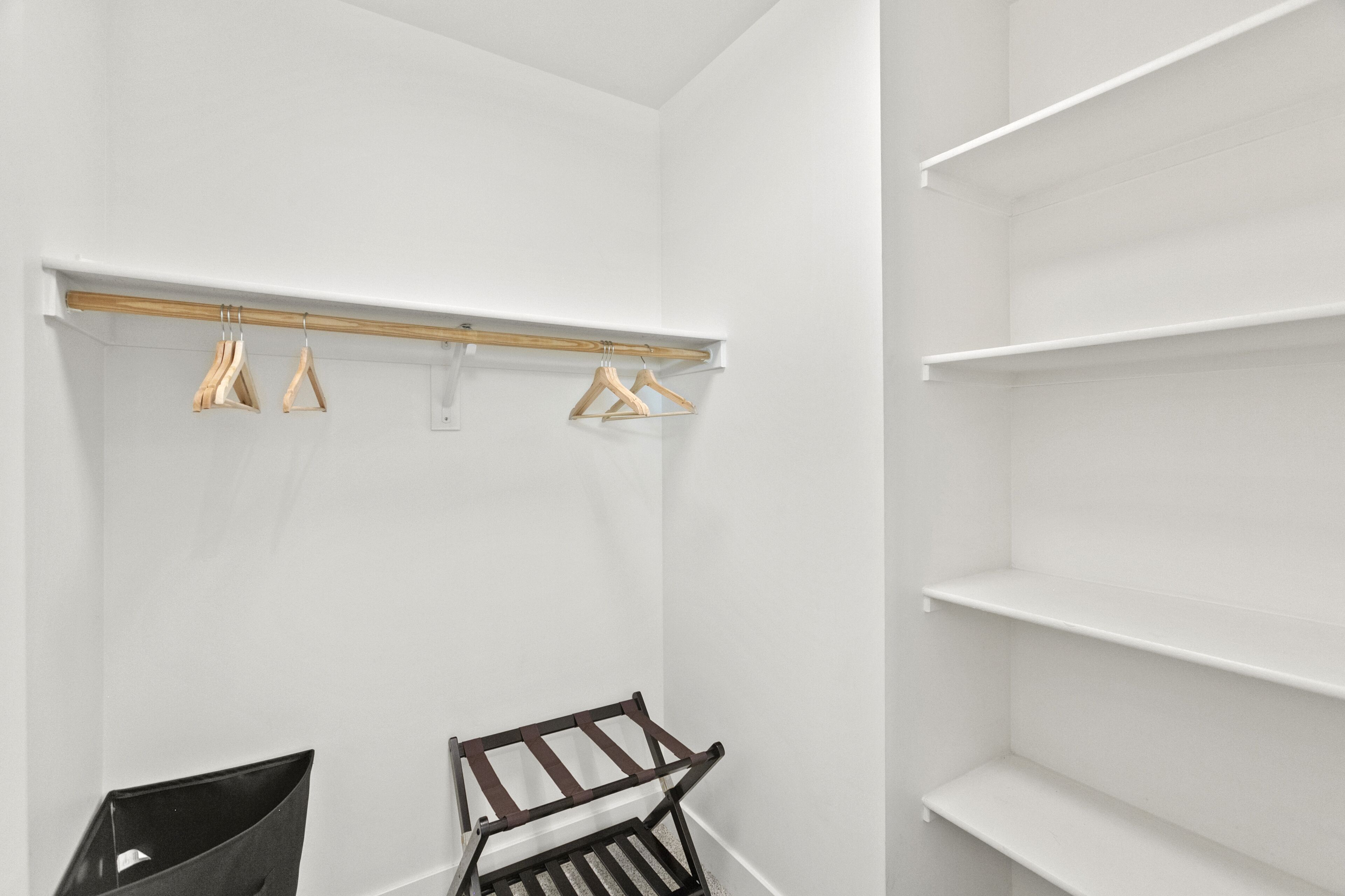Ein weißer Kleiderschrank mit Holzleisten und Regalen.