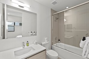A modern bathroom with a white sink, toilet, and bathtub. There is a glass-enclosed shower area and a large mirror above the sink. - Pueblo Suite - Walk to all things OT Scottsdale (Scottsdale)