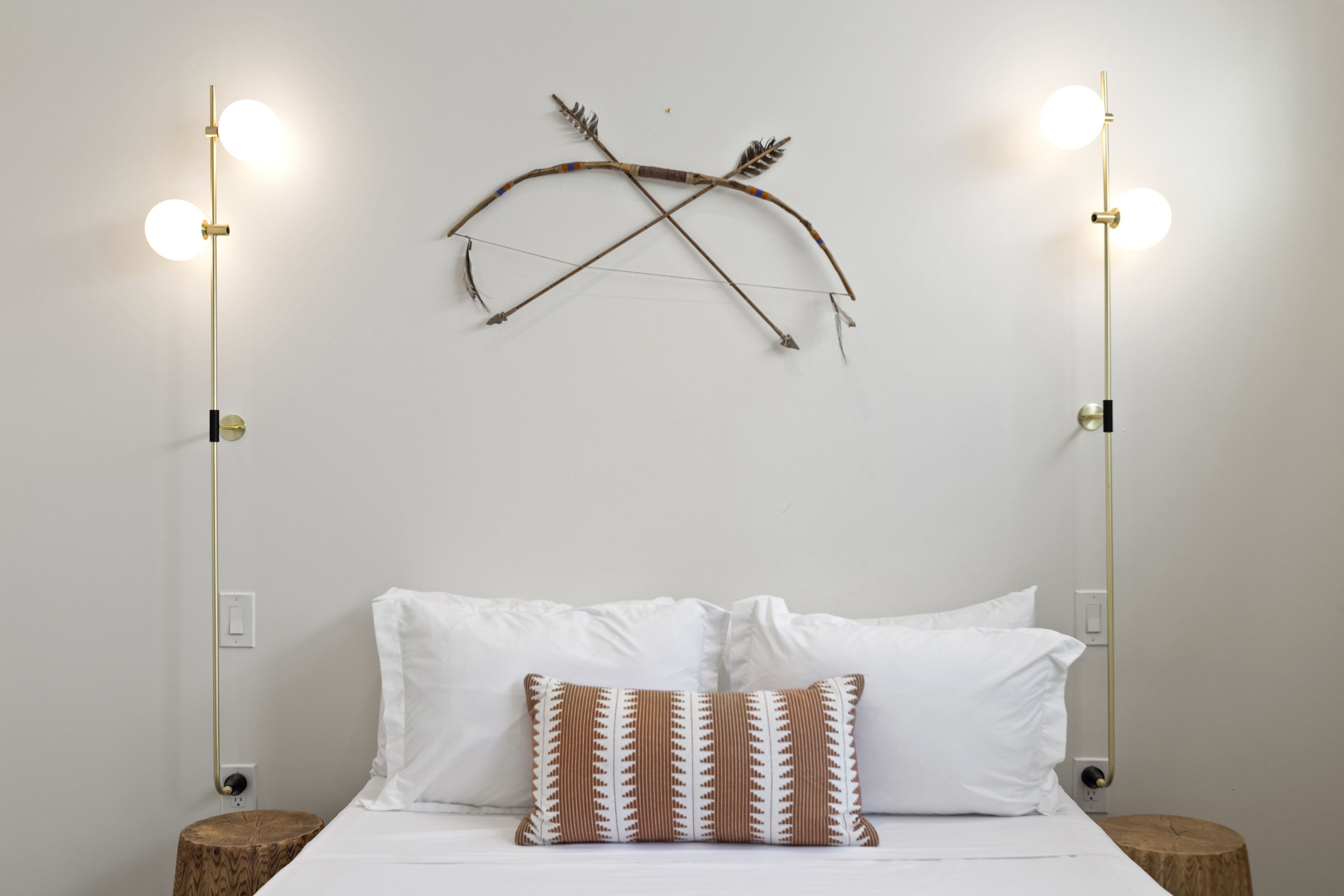 A bed with white linens, a patterned pillow, and two bedside tables with lamps.