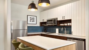 A modern kitchen with a central island, stainless steel appliances, and a blue-tiled backsplash. - Staybridge Suites Lexington S Medical Ctr Area (Lexington)
