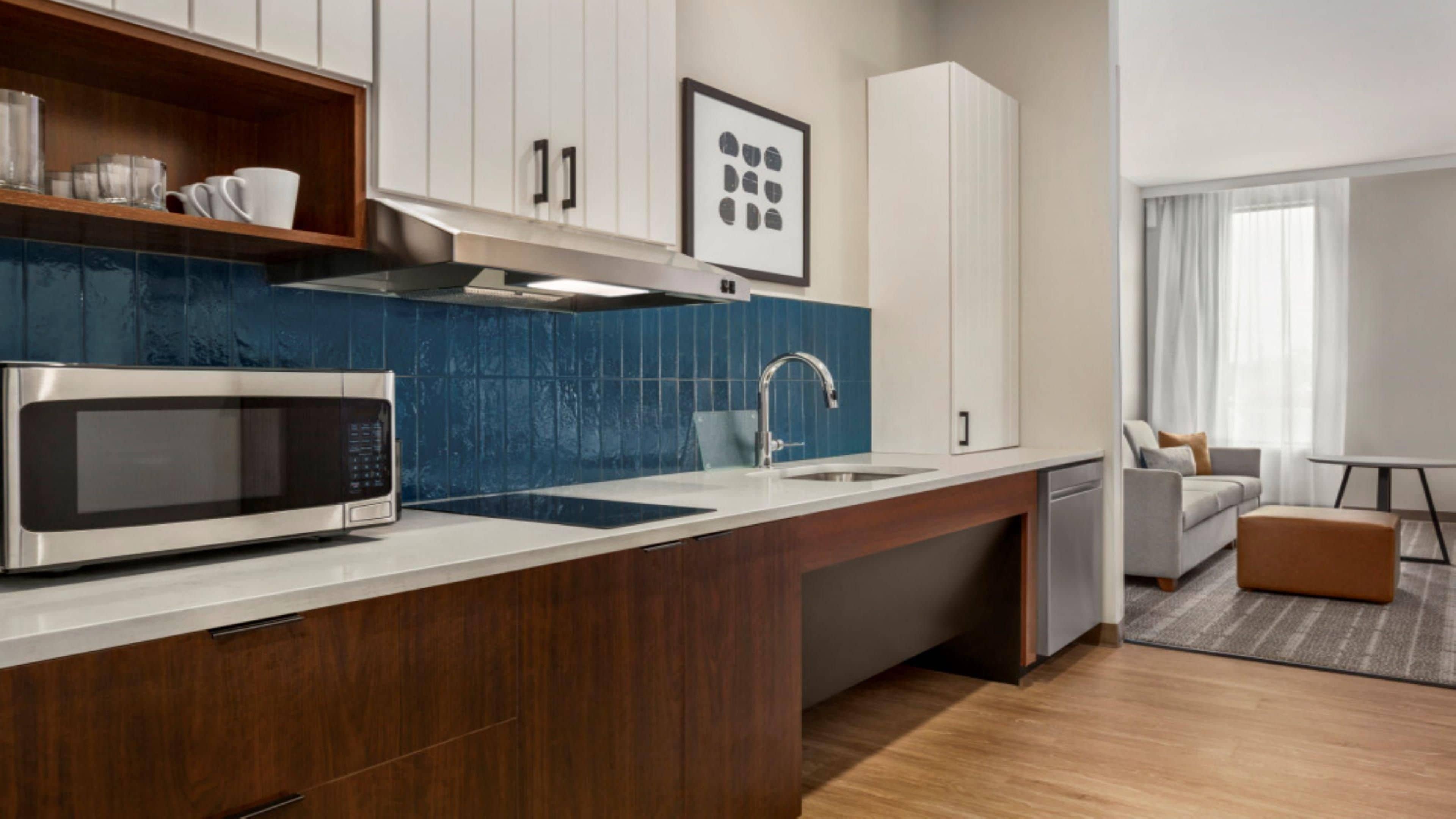 Una cocina moderna con microondas, lavamanos y armarios de madera.