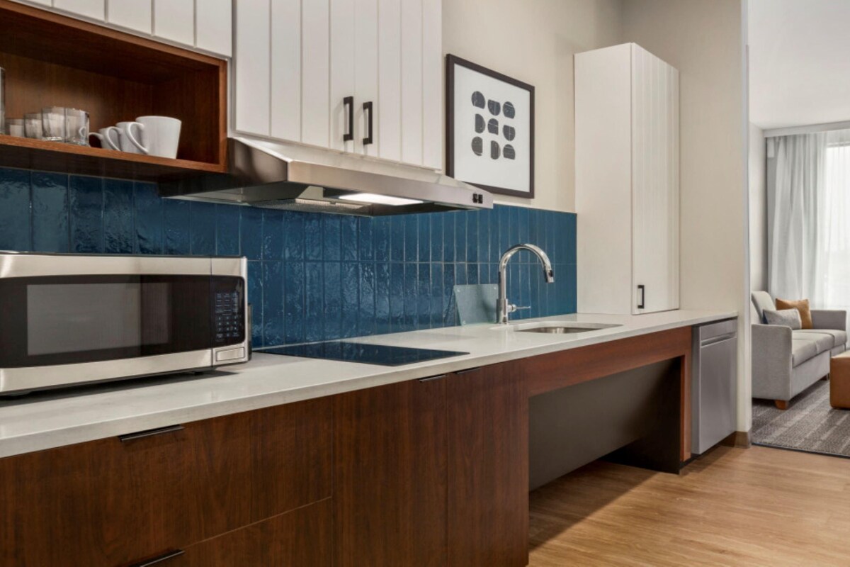 Una cocina moderna con microondas, lavamanos y armarios de madera.