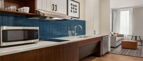 Una cocina moderna con microondas, lavamanos y armarios de madera.