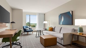 A hotel room with a sofa, armchair, desk, and a TV. - Staybridge Suites Lexington S Medical Ctr Area (Lexington)